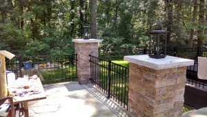 custom stone pillars with landscape lighting and aluminum fencing connected