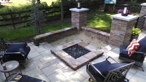 custom square fire pit in corner bordered by lawn chairs and retaining walls